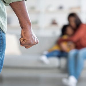 A man stands angrily while a woman holds his daughter in front of him, representing domestic violence during a divorce. - Yarbrough Law Firm