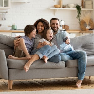 A happy couple smiling with their adopted children, all sitting together on a couch - Yarbrough Law Firm